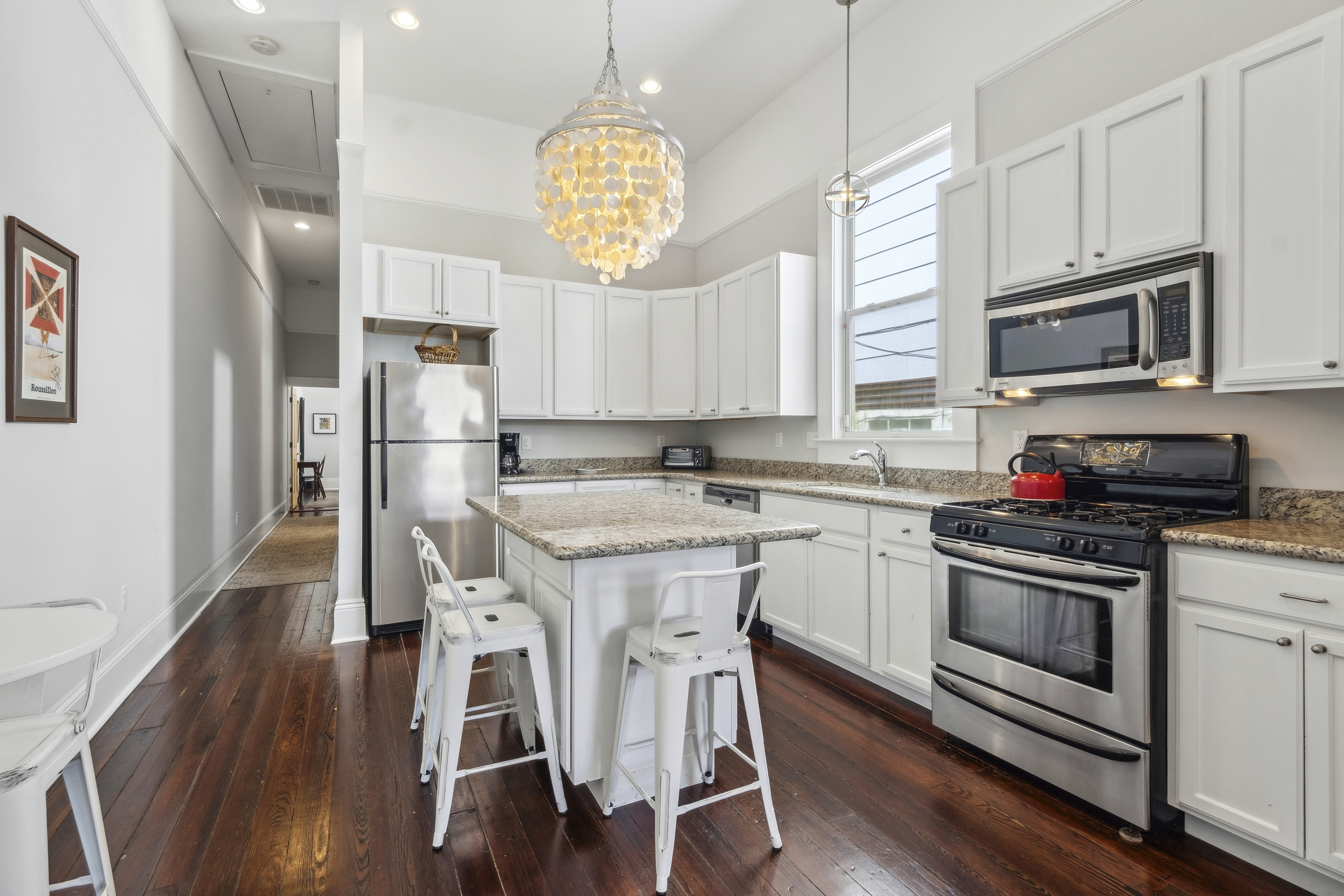 Renovated white kitchen with granite island, gas range, and stainless appliances
