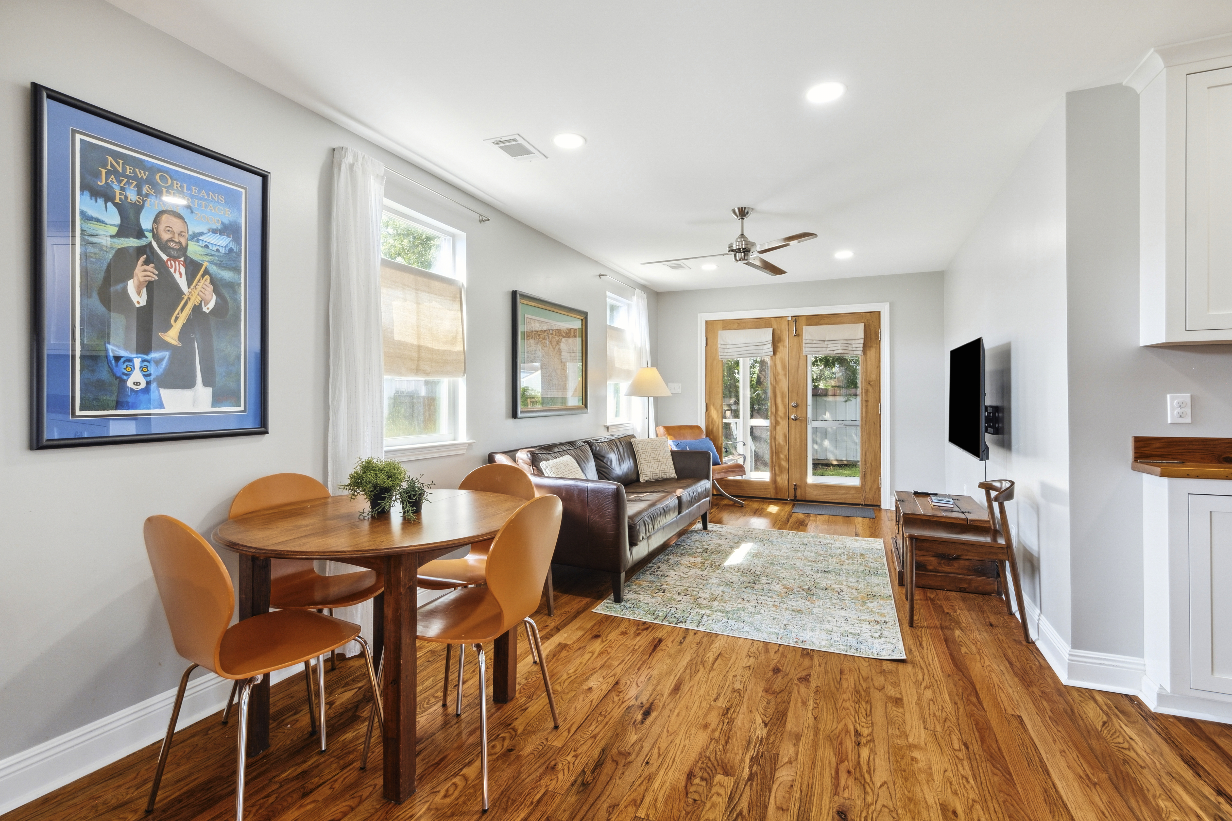 Bright living and dining area with a New Orleans Jazz Fest poster and hardwood floors
